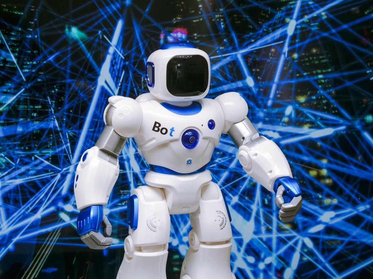 A white and blue humanoid robot standing in front of a glowing blue network